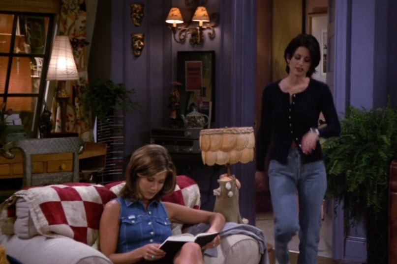 Monica porte le Mom jeans, dans son appartement, sous un cardigan. 