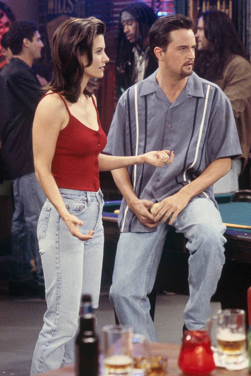 Monica et Chandler sont dans un bar. Tous deux porte un jean taille haute, blanchi. 